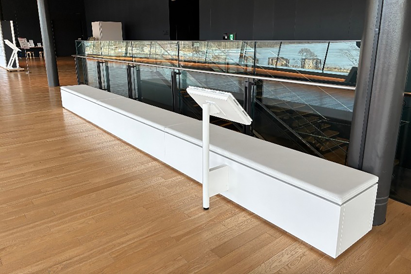 A monitor stand in front of a long white bench