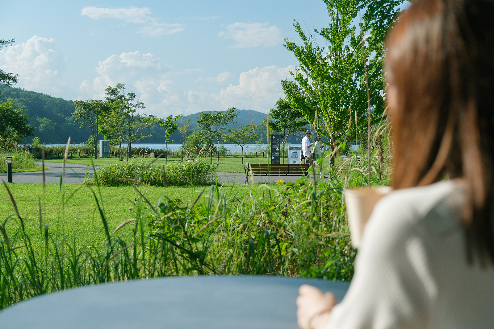 テラス席でコーヒーを手に湖を眺める女性